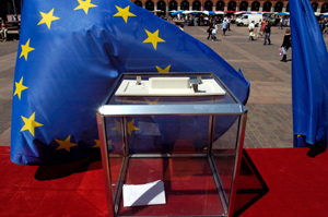 A clear ballot box in front of the european union flag.