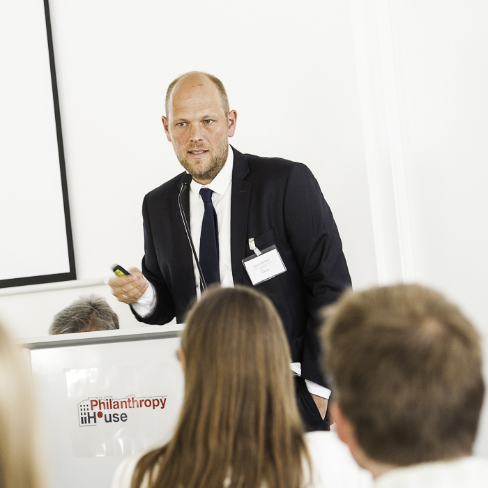 A man in a suit talking at a podium (Espen Olsen).