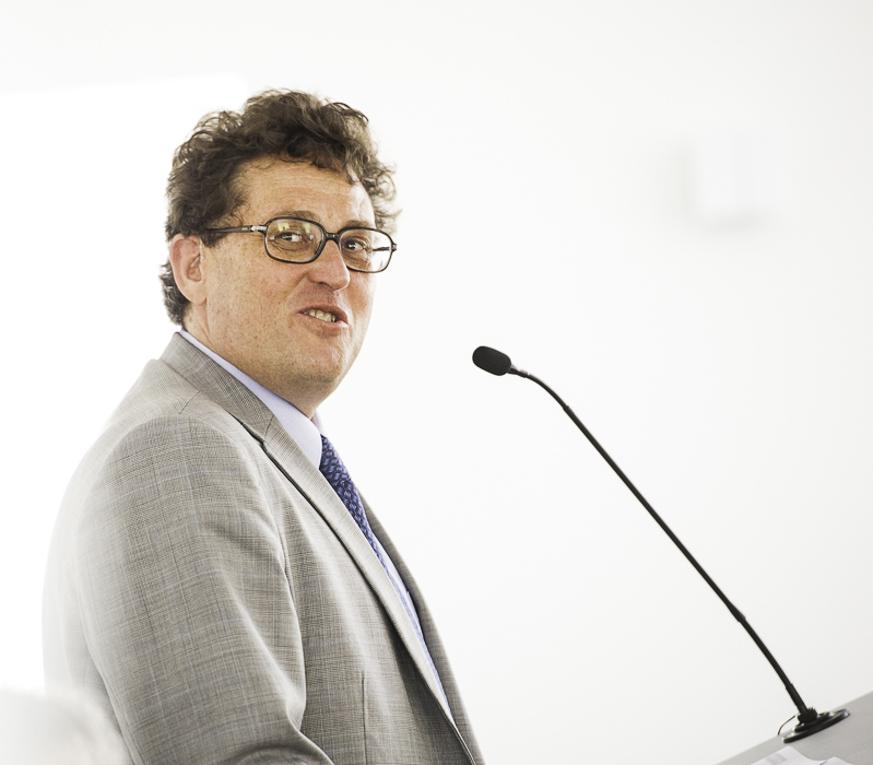 A man with curly hair and glasses talking in a microphone (René Schwok).