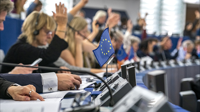 People at the European Parliament raising hands.