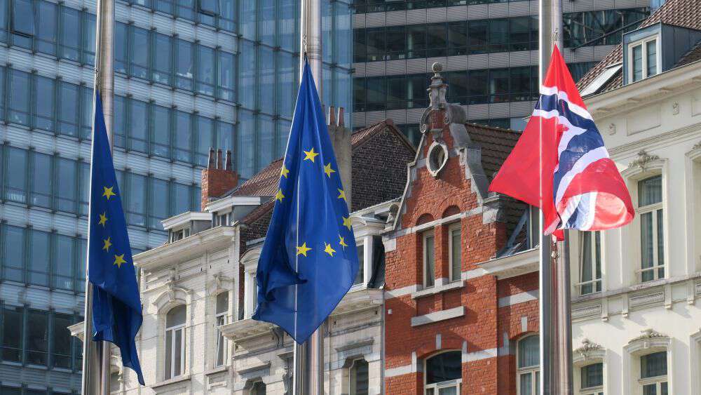 Norsk og EU-flagg foran bygninger