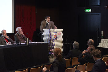 Chair ,Coat ,Public address system ,Spokesperson ,Suit.