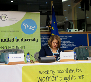 En kvinne sitter ved en stand med teksten "Women together for women's rights and..."
