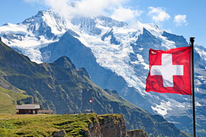 Det sveitsiske flagget med fjell i bakgrunnen