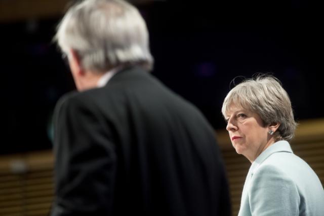 Bilde av Theresa May som ser litt trist på Jean-Claude Juncker. 