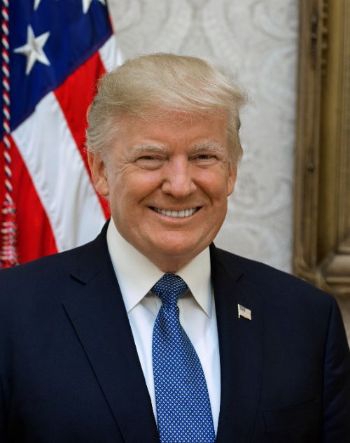 Donald Trump smiling in a suit and a blue tie