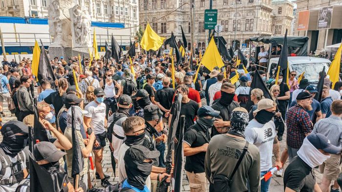 crowd in protest, many wearing black face covers and waving black or yellow flags