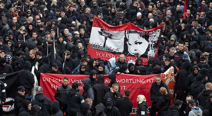 large crowd wearing black clothes and carrying red banners
