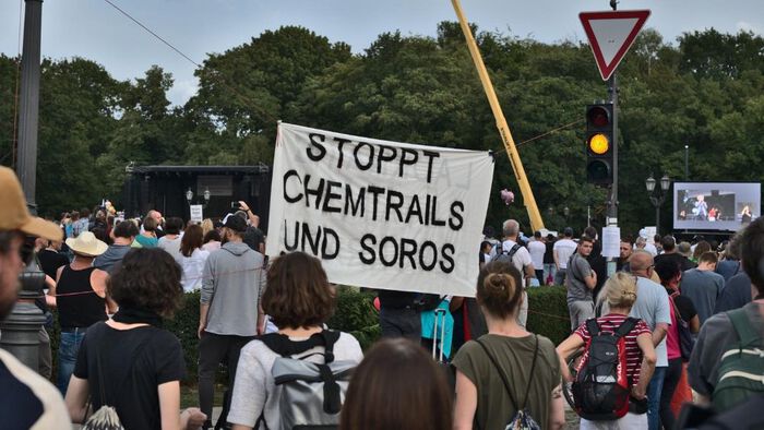 protest, one person carrying a sign that saus "stoppt chemtrail und soros"