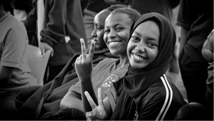 two young people smiling and doing the peace sign