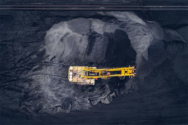 Yellow excavator in a large coal mine.