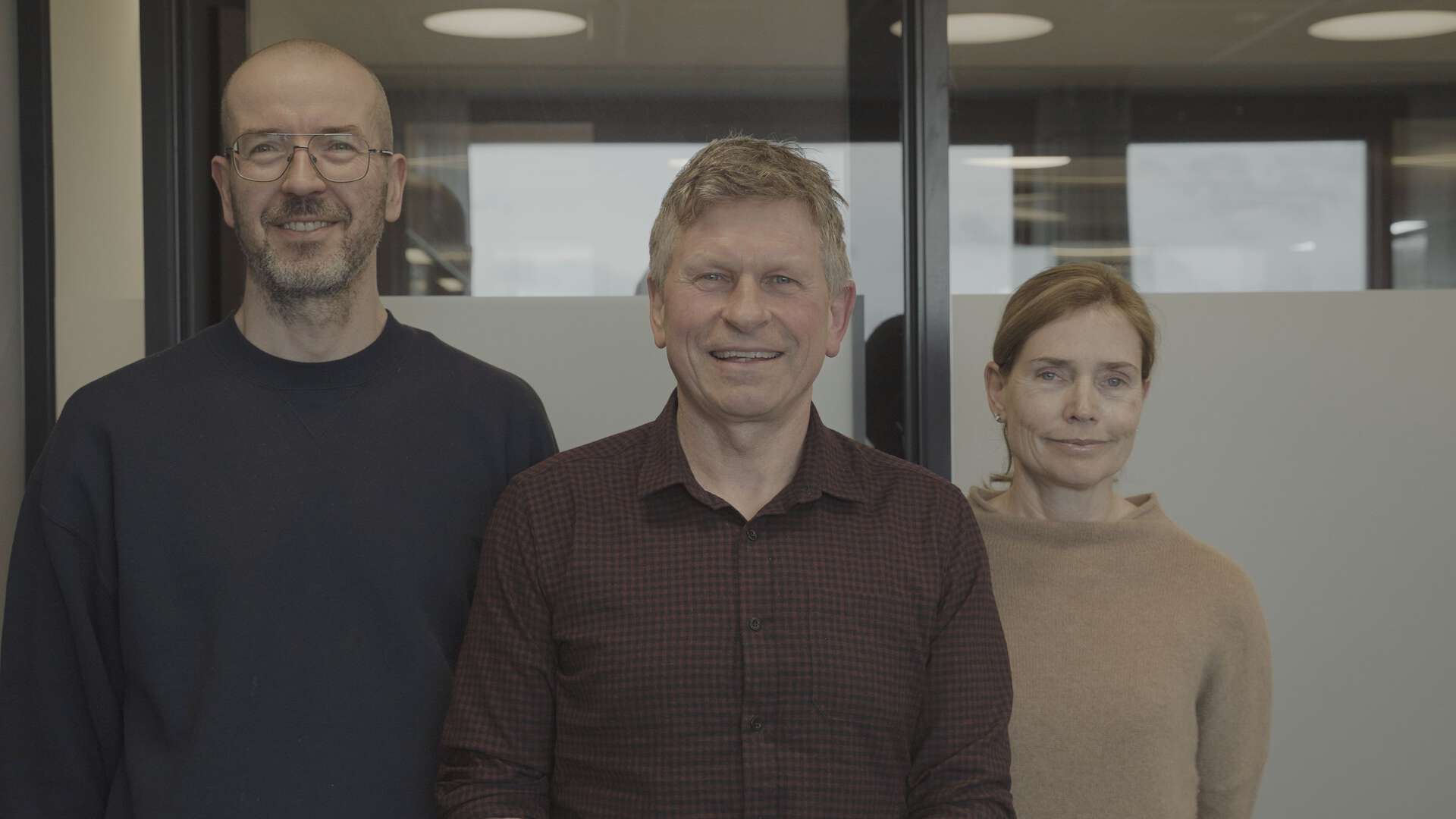 1 kvinne og 2 menn står smilende og ser i kamera