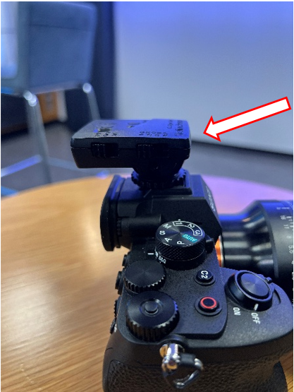 Top of the camera with the Elinchrom unit attached, with an arrow showing the mounting screw to loosen