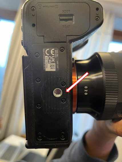 Underside of the camera, with an arrow pointing to the mounting hole for the quick-release plate