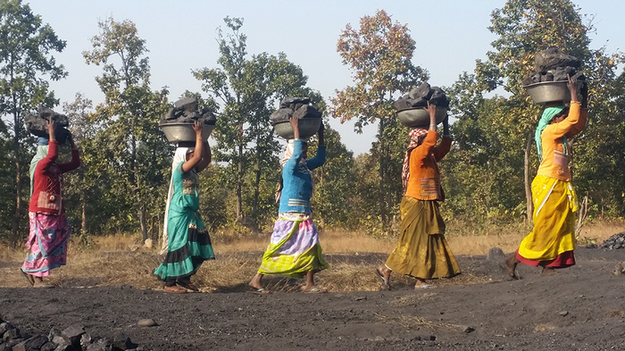 Five Adivasis women carrying baskets with coal on their heads