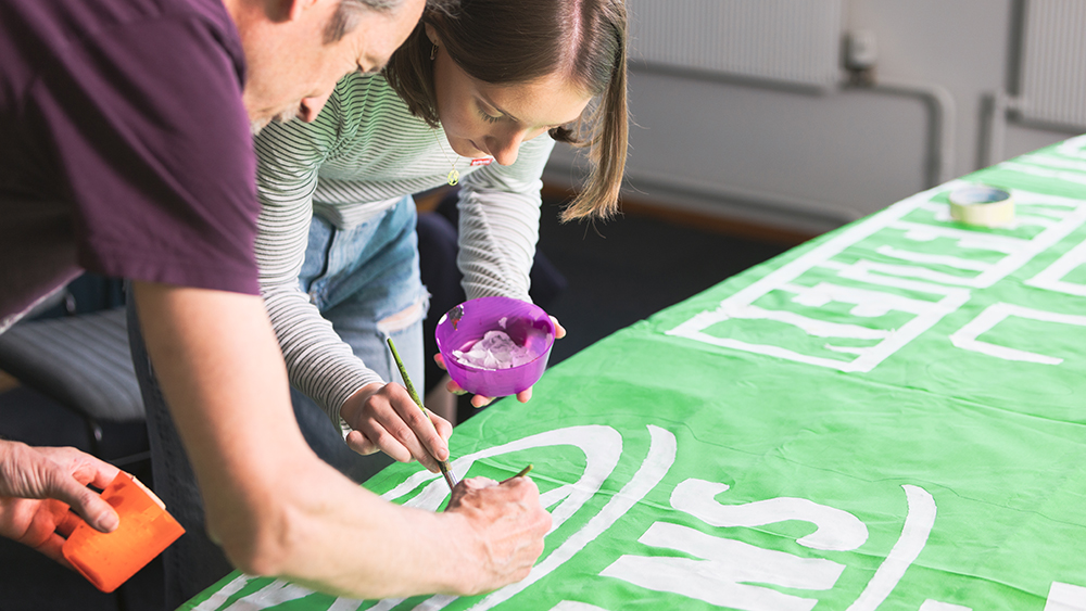 Man and woman painting a banner