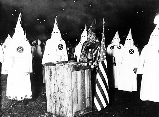 Ku Klux Klan i Chicago omkring 1920. Flere hvitkledde mennesker med hetter. I midten et slags alter og et amerikansk flagg