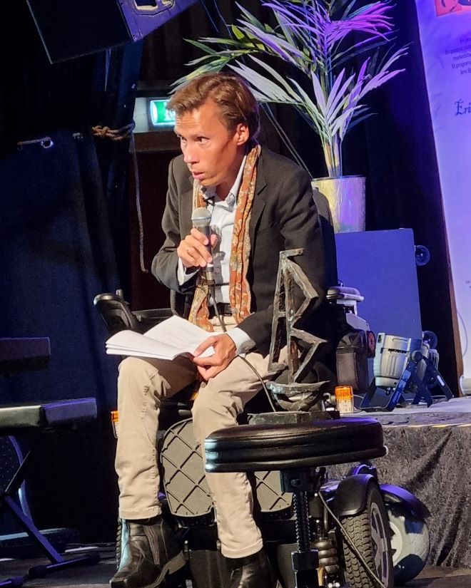 Mann i rullestol med mikrofon på en scene