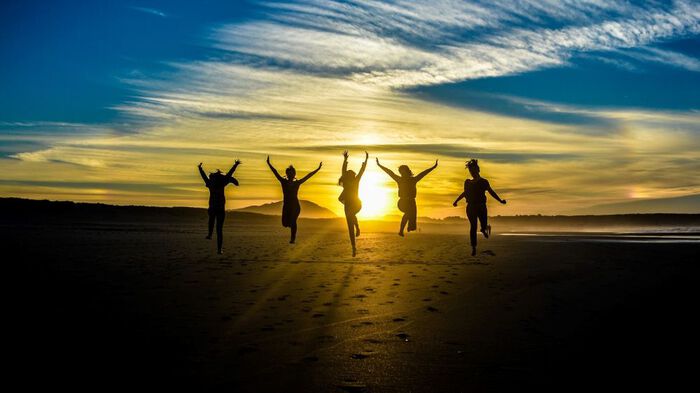 Five people on a beach during sunset
