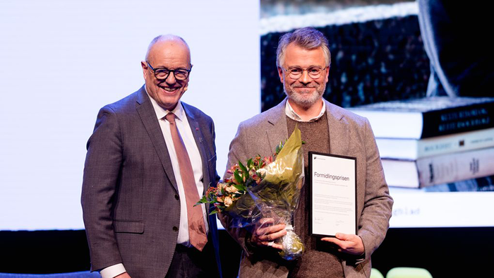 Gunnar Bovim og Magne Flemmen på scenen med blomster og diplom