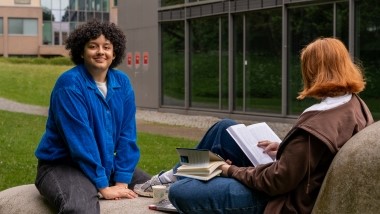two students studying on a big rock outside