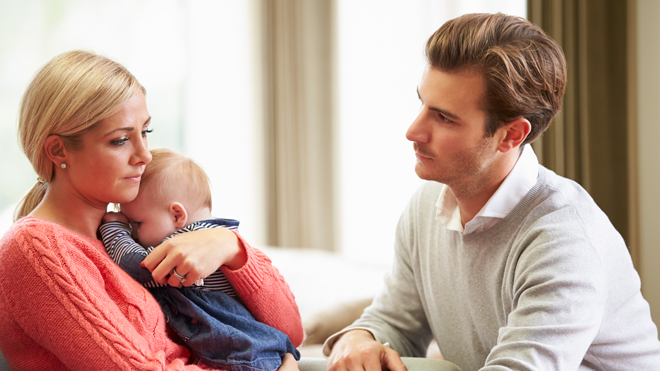 Mor holder baby og far ser på dem.