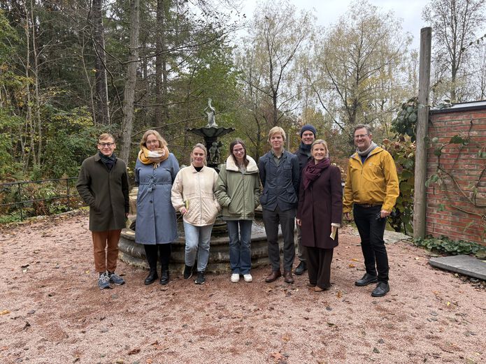 Eight smiling people standing outside