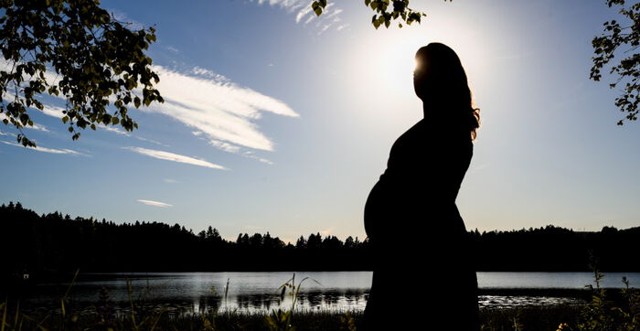 Gravid kvinne ved et vann.
