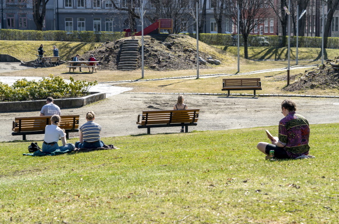 Grupper av mennesker sitter med korrekt avstand i park.