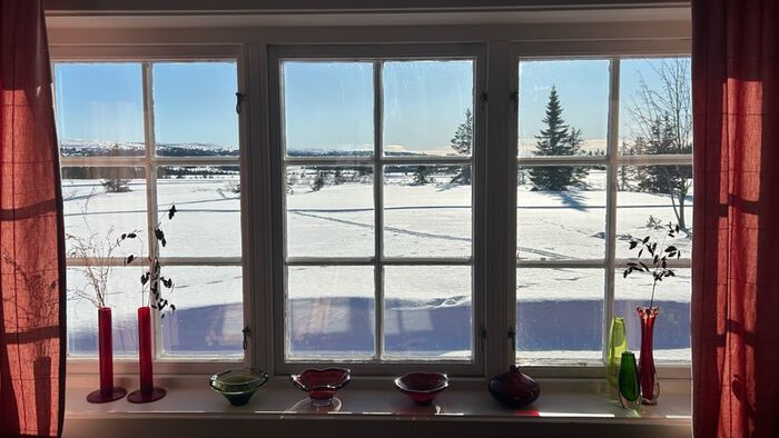 Vindu mot snø og solfylt landskap
