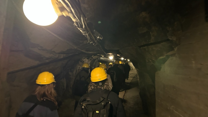 People with yellow helmets walking in an underground mining spot. 