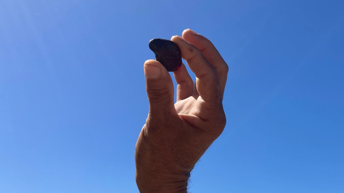  A piece of Sicilian amber held in a hand against the blue sky