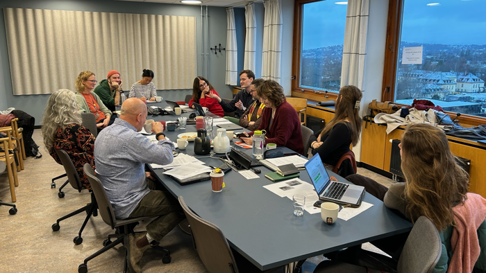A group of people seated around a table in the middle of a discussion.