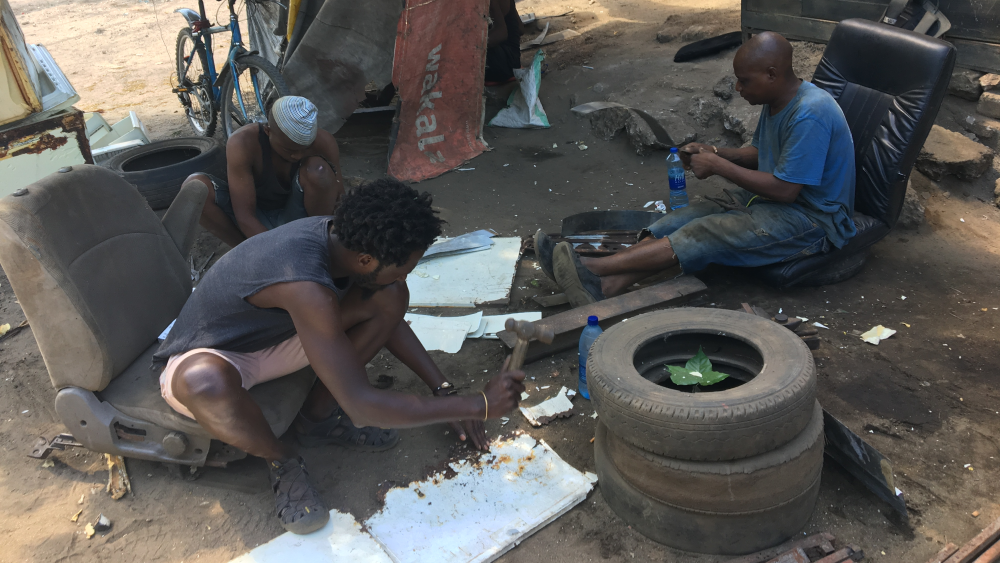 Three people sitting in old seats on the ground working