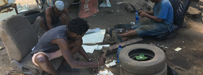 Three people sitting in old seats on the ground working