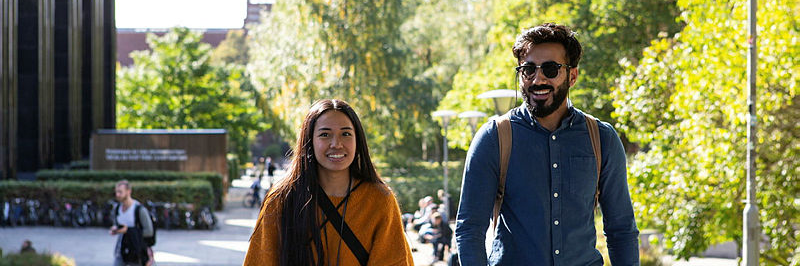 kvinnelig og mannlig student går smilende på Blindern