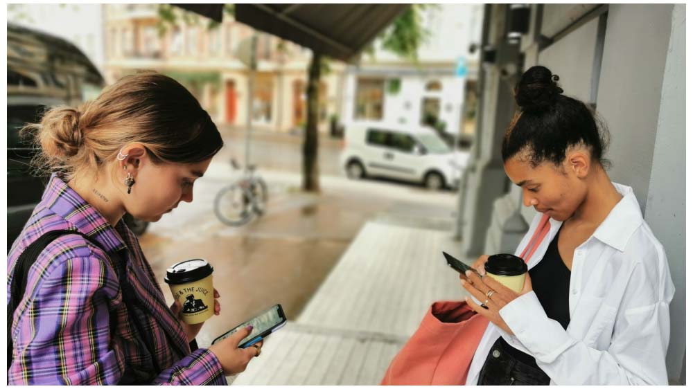 To jenter står sammen med hver sin smarttelefon