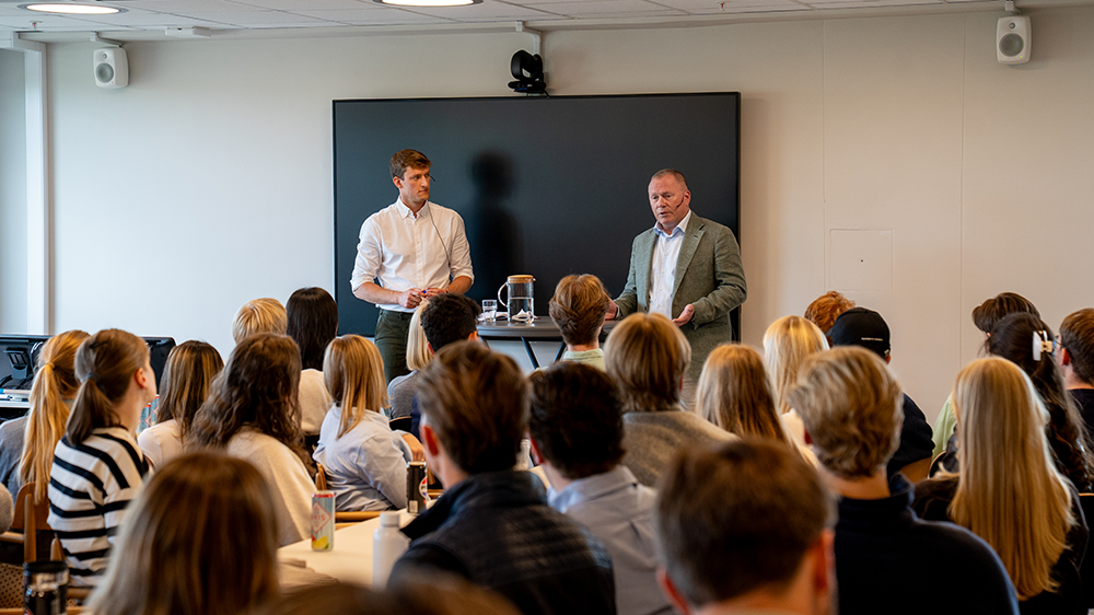 Nicolai Tangen og Torje Hegna i et rom foran lyttende studenter