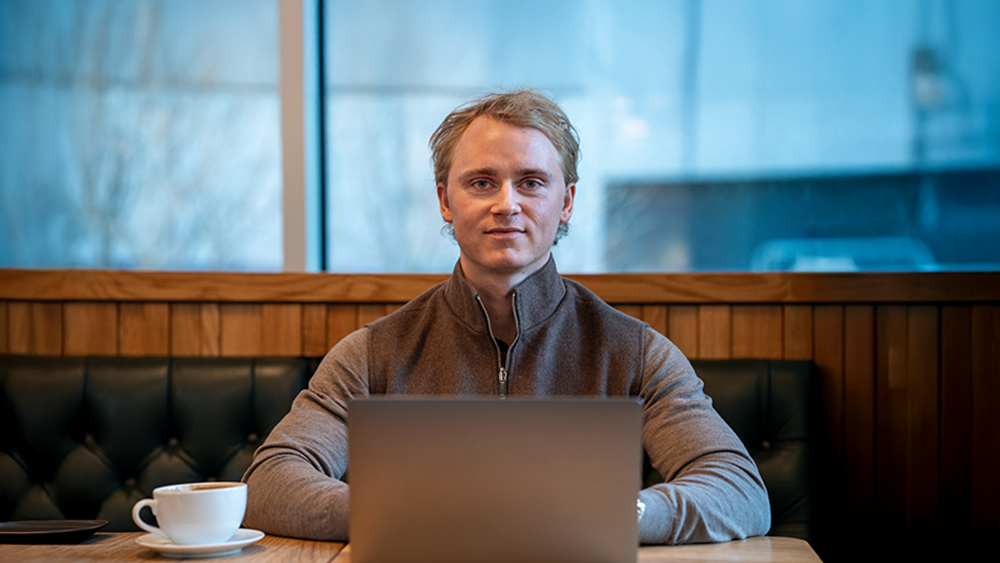 Magnus Gretton, som har en bachelor i økonomi og finans ved Universitetet i Oslo, på kafé foran laptop
