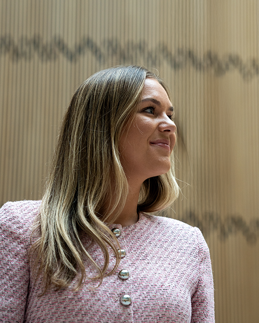 Sara Midtgaard foran plankevegg, ser opp mot lyset