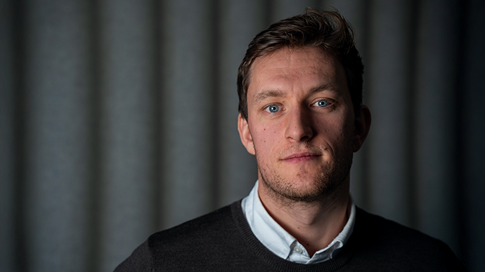 Portrett av programleder for økonomi og finans foran grå vegg
