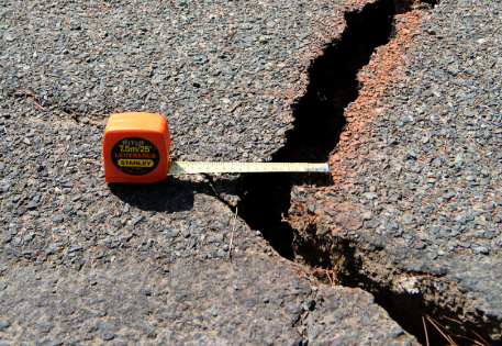 A crack in the pavement with measuring tape laid across it